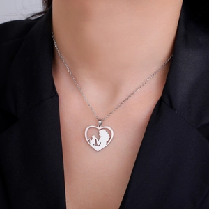 Detail of silver heart necklace featuring a silhouette of a woman and cat on a black suit
