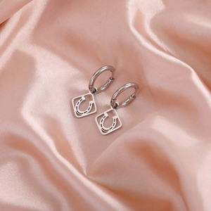 Detailed macro of silver stainless steel hoop earrings with square star pendants on satin