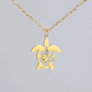 Detail of 18k gold plated turtle pendant featuring hollow hibiscus flower pattern
