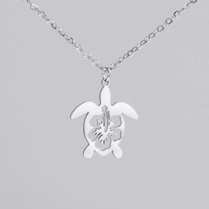 Detail of silver turtle pendant featuring hollow hibiscus pattern on polished steel