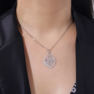 Detailed view of silver spiral geometric pendant necklace worn on a black blazer