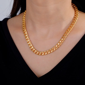 Close-up of a classic gold-plated cuban link chain worn by a model in a black outfit