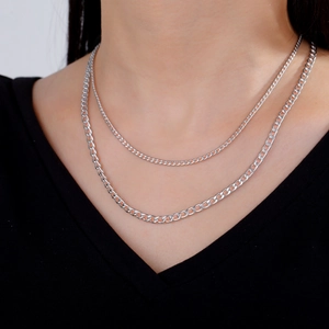 Detail of layered silver cuban link chain necklace on model for classic punk style