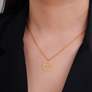Close-up of golden hollow butterfly pendant necklace worn by model on black blazer