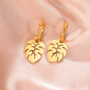 Elegante 18K vergoldete Monstera Blatt Creolen auf weichem lila Satinhintergrund