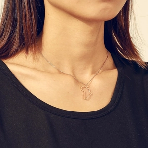 Close-up of a hollow Africa map pendant necklace in gold finish worn by a model