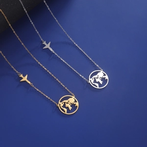 Gold and silver world map airplane necklaces on a deep blue textured surface