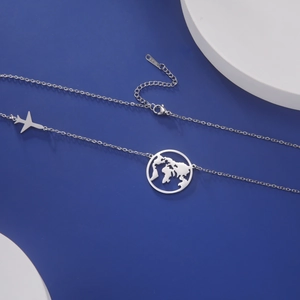 Detailed shot of silver airplane and world map pendants on a stainless steel chain