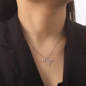 Detalle de un colgante de corazón de plata con alas en una fina cadena de collar largo
