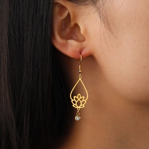 Elegant gold lotus drop earrings with hollow design and round clear zircon on model