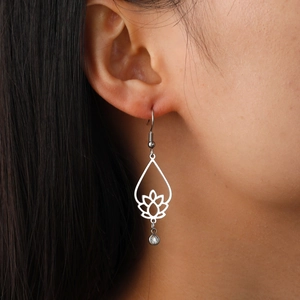 Silver hollow teardrop earring with lotus pattern and clear crystal on a model