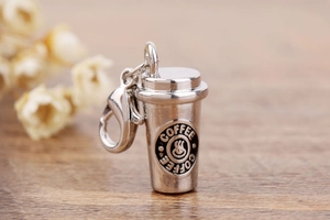 Detailed shot of coffee cup charm with lobster clasp on a rustic wooden surface
