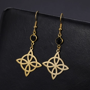 Détail de boucles d'oreilles nœud de sorcière dorées en titane avec strass noirs sur cuir