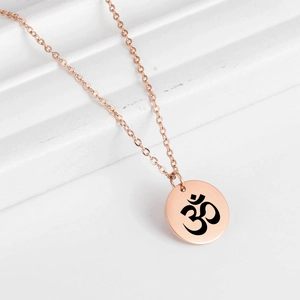 Gros plan du pendentif Om yoga or rose sur une chaîne fine en acier inoxydable