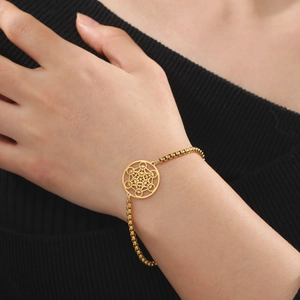 Bracelet doré avec pendentif Cube de Métatron et chaîne à billes au poignet féminin