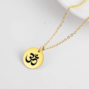 Gros plan du pendentif rond doré en acier inoxydable avec symbole Om yoga gravé