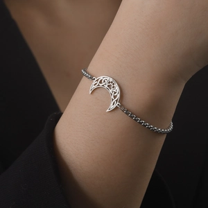 Détail du bracelet chaîne en argent avec pendentif croissant de lune et patte au poignet