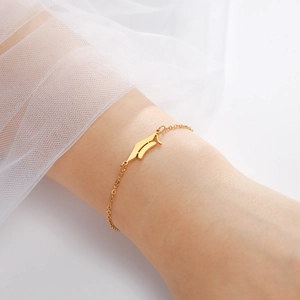 Detail of a gold Old English letter A pendant on an O-chain bracelet worn by a model