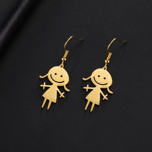 Macro detail of golden stainless steel cartoon girl earrings on black leather background