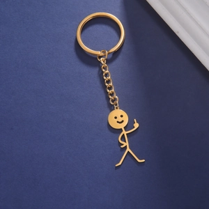 Close-up of golden stick figure keychain with funny middle finger gesture on blue background