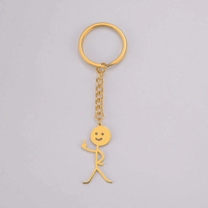 Detailed macro of a funny gold-plated stick figure keychain with a middle finger gesture
