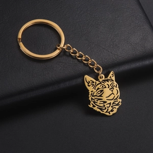 Detailed view of a gold cutout cat head keychain on textured black leather surface