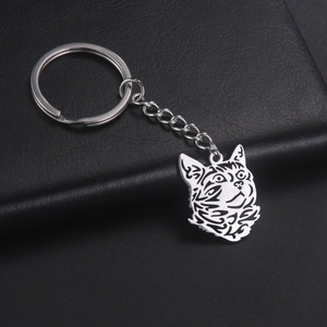 Artistic cat head metal keychain with tribal pattern on black leather background