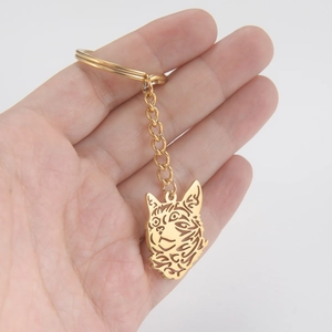 Golden hollow cat head pendant keychain made of stainless steel held by a hand
