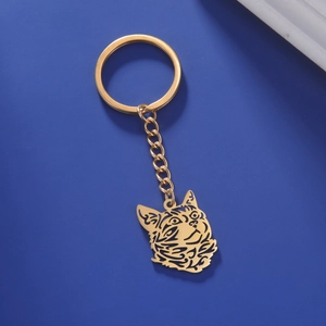 Close-up of golden hollowed-out cat pendant on stainless steel keychain with dark blue background
