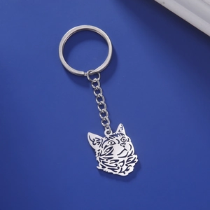 Detail shot of hollowed-out cat head keychain pendant in silver metal on blue background