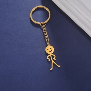Detail eines goldenen Stickman-Anhängers mit Smiley-Gesicht auf blauem Hintergrundgewebe