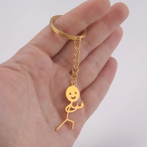 Detailed shot of funny gold stickman keychain with middle finger gesture in hand
