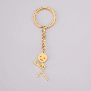 Macro detail of gold stickman keychain with smiley face and middle finger gesture