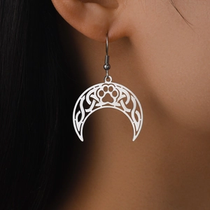 Macro shot of silver crescent moon earrings with celtic knot and animal paw cutout details