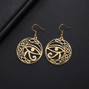 Gold Eye of Horus drop earrings with cutout patterns on textured black background