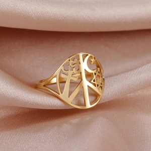 Macro detail of gold hollow ring featuring peace, cross, and star symbols on silk