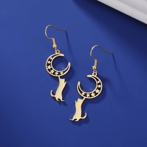 Detail of gold moon and star earrings with a cat silhouette against a blue background