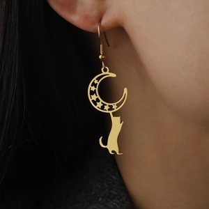 Gold cat on moon earrings with hollow stars and crescent design on a model's ear