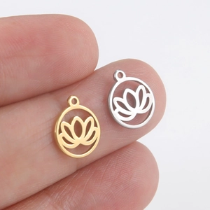 Pendentifs lotus en acier poli doré et argenté présentés sur le bout des doigts