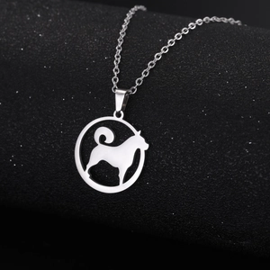 Minimalist silver dog silhouette pendant necklace on a textured black surface