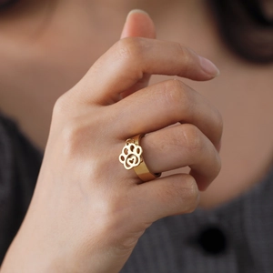 Gouden roestvrijstalen ring met een hangende hartvormige pootafdruk bedel aan de vinger