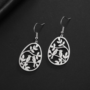 Boucles d'oreilles oiseaux en acier argenté avec motif nature creux sur fond noir