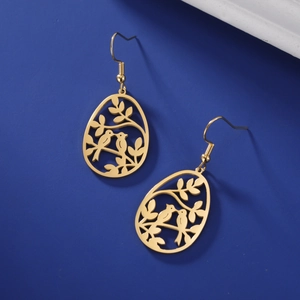 Détail de boucles d'oreilles dorées avec motifs branches et oiseaux ajourés polis
