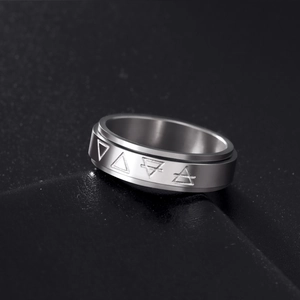 Detail of brushed silver stainless steel ring with engraved triangle symbols on black background