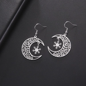 Detailed view of silver snowflake and moon dangle earrings on a black background