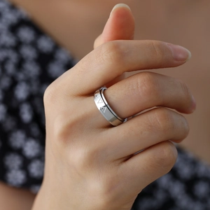 Male hand wearing a spinning stainless steel ring with engraved triangle patterns