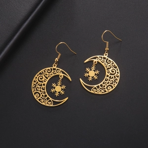 Detail of golden crescent moon earrings with intricate filigree and snowflake charms