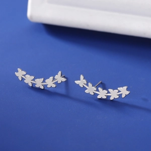 Detail shot of five silver butterfly stud earrings in a curved design on blue background