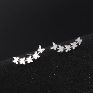 Macro shot of silver butterfly stud earrings in a curved design on black display