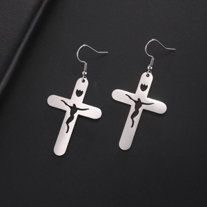 Détail de boucles d'oreilles croix argentées avec silhouette humaine et découpe de tulipe noire